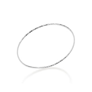 Sterling silver bangle bracelet on a reflective white background showcasing a delicate circular silhouette with an etched diamond-cut texture and high-polish finish