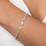 Sterling silver snake chain bracelet by Rommanel worn on a wrist featuring an engraved butterfly clasp and a miniature crown charm