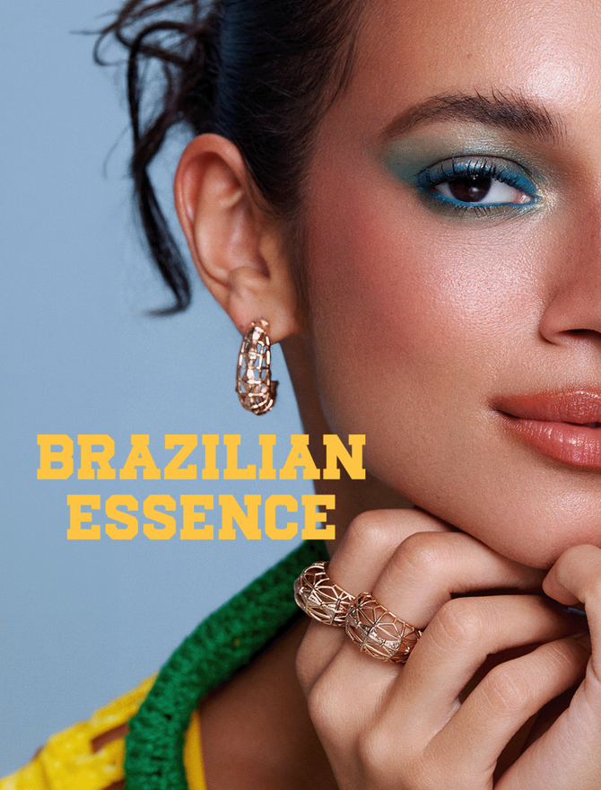 Model wears blue eye makeup, terracotta lipstick, and three intricate gold cage-style rings.
