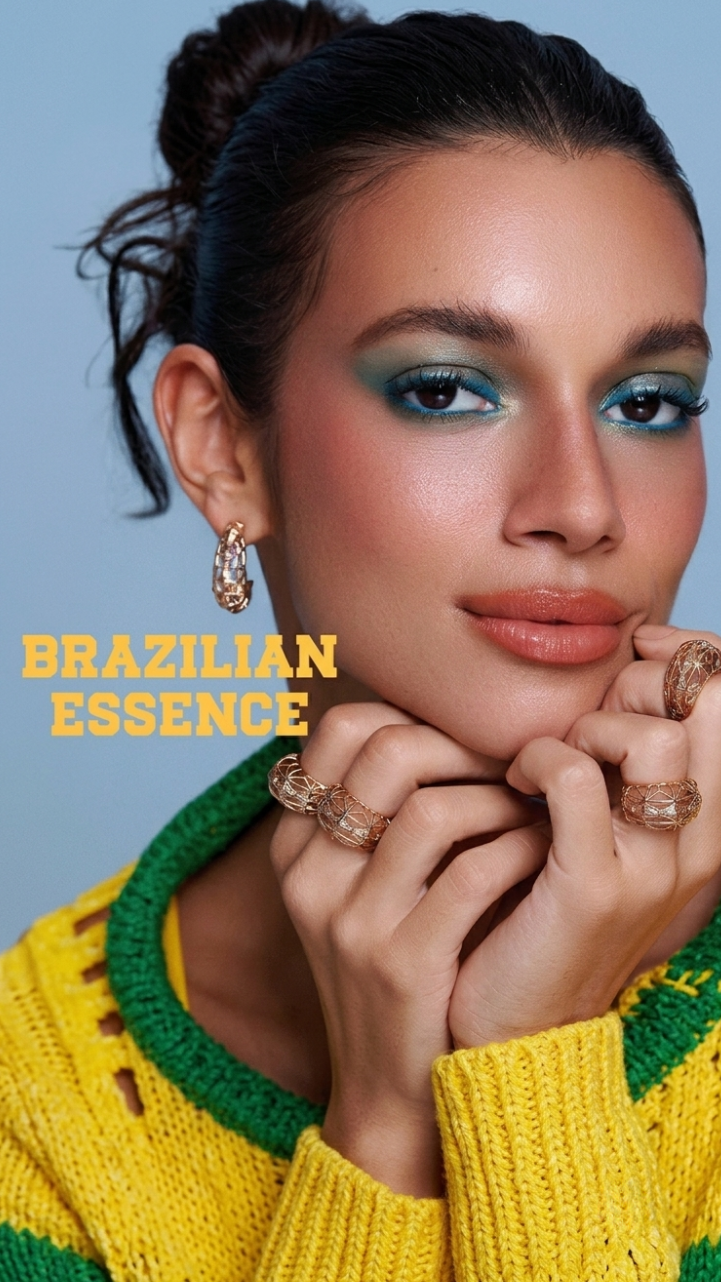 Model wears blue eye makeup, terracotta lipstick, and three intricate gold cage-style rings.