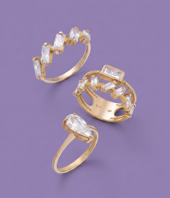 Set of three gold rings featuring baguette and teardrop cubic zirconia stones.