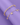 Two gold bracelets stacked together over a purple surface: a trendy thick ball-and-gauge link chain bracelet, alongside a thin chain bracelet decorated with dangling seashell and pearl charms.