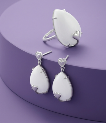 Silver jewelry set featuring teardrop white stones with heart accents on ring and drop earrings.