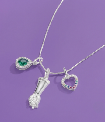 Silver chain necklace with green teardrop crystal, figa fist, and rainbow heart pendats.