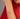 A model wears two delicate gold chain bracelets, each featuring an open heart pendant, stacked on her wrist against a red shirt.