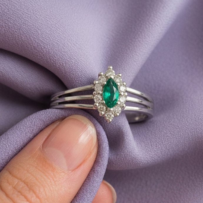 Silver marquise cluster ring with a marquise-cut emerald and diamond halo.