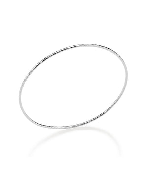 Sterling silver bangle bracelet on a reflective white background showcasing a delicate circular silhouette with an etched diamond-cut texture and high-polish finish