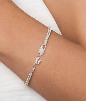 Sterling silver snake chain bracelet by Rommanel worn on a wrist featuring an engraved butterfly clasp and a miniature crown charm