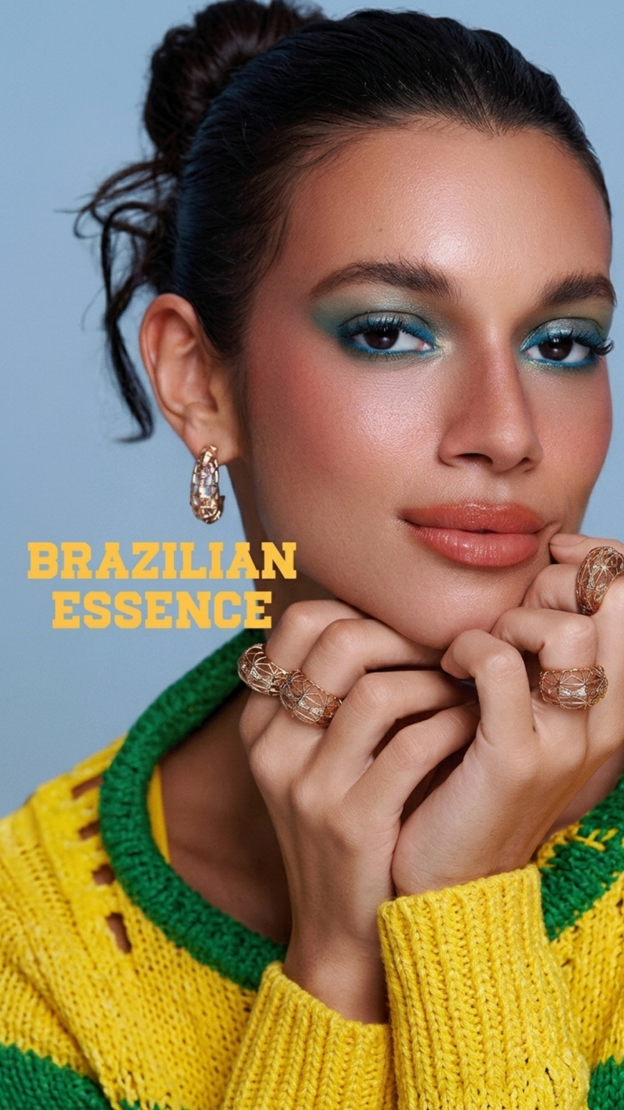 Model wears blue eye makeup, terracotta lipstick, and three intricate gold cage-style rings.