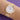 A gold-toned Rommanel watch on a wrist with a textured gold mesh band, a white face, and numbers 12 and 6.